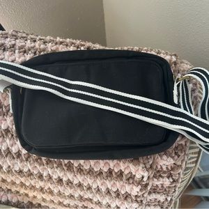 31. Crossbody, all zipped up bag in black with white and black strap.
